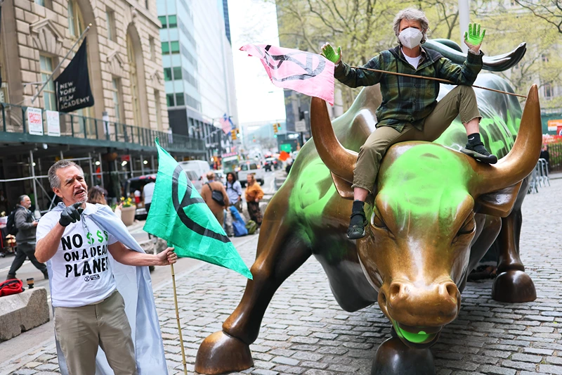 NEW YORK, NEW YORK - APRIL 22: Climate activist hold a protest at the Charging Bull statue in Bowling Green near the New York Stock Exchange on April 22, 2025 in New York City. Members of the climate activist group Extinction Rebellion vandalized the Charging Bull on Earth Day to protest what they say is Wall Street's complicitness in climate change. (Photo by Michael M. Santiago/Getty Images)