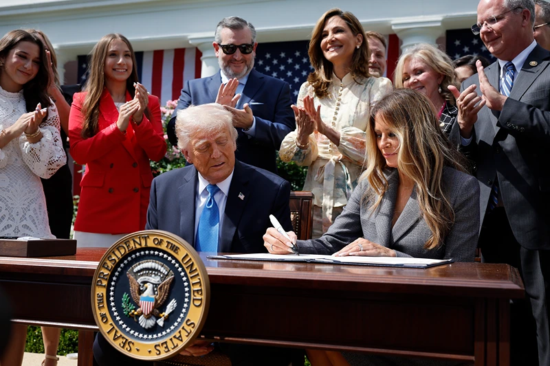 First lady Melania Trump signs the TAKE IT DOWN Act alongside U.S. President Donald Trump, lawmakers and victims of AI deepfakes and revenge porn, during a signing ceremony in the Rose Garden of the White House on May 19, 2025 in Washington, DC. The first lady made the Tools to Address Known Exploitation by Immobilizing Technological Deepfakes on Websites and Networks (TAKE IT DOWN) Act a priority, traveling to Capitol Hill to lobby lawmakers and show her support for the legislation, which addresses non-consensual intimate imagery, or "revenge porn," and artificial intelligence deepfakes posted online and to social media. (Photo by Chip Somodevilla/Getty Images)