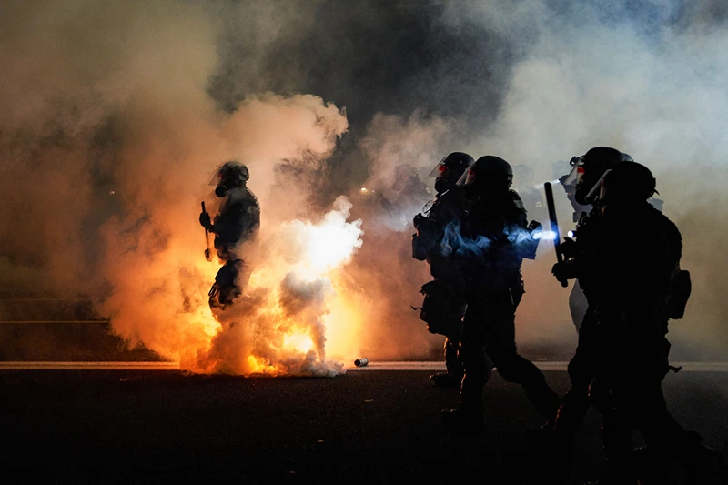 TOPSHOT - Oregon Police wearing anti-riot gear march towards protesters through tear gas smoke during the 100th day and night of protests against racism and police brutality in Portland, Oregon, on September 5, 2020. Police arrested dozens of people and used tear gas against hundreds of demonstrators in Portland late on September 5 as the western US city marked 100 days since Black Lives Matter protests erupted against racism and police brutality. Protests in major US cities erupted after the death of African American George Floyd in May 2020 at the hands of a white police officer in Minneapolis. (Photo by Allison Dinner / AFP) (Photo by ALLISON DINNER/AFP via Getty Images)
