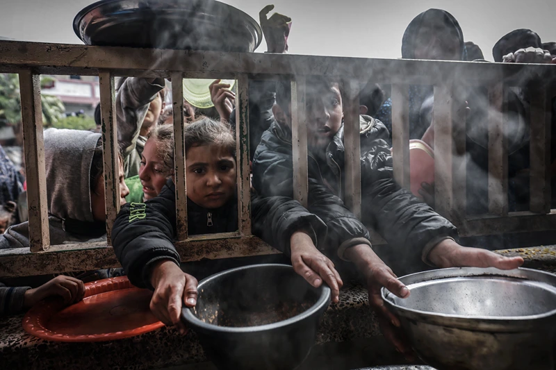 TOPSHOT - Displaced Palestinian children gather to receive food at a government school in Rafah in the southern Gaza Strip on February 19, 2024, amid the ongoing battles between Israel and the militant group Hamas. The UN children