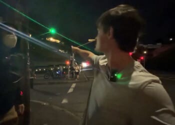 A masked antifa thug, left, was seemingly unaware of the sniper's green laser sight dot until the podcaster called his attention to it.