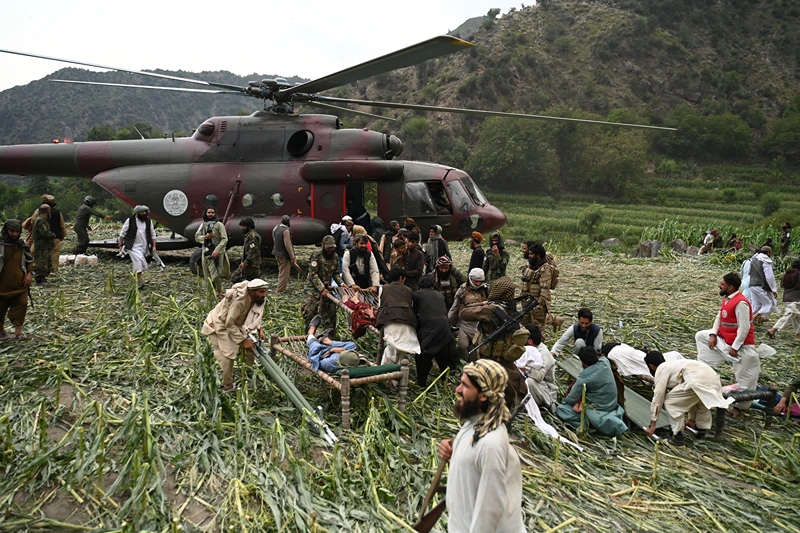 Afghan volunteers and Taliban security personnel work to move injured people near a military helicopter following earthquakes in the Mazar Dara village of Nurgal, a district of the Kunar Province, in Eastern Afghanistan, on September 1, 2025. More than 800 people have died and over 2,700 were injured from August 31 night to September 1, 2025, in eastern Afghanistan after a 6-magnitude earthquake, followed by at least five aftershocks felt hundreds of kilometers away. (Photo by Wakil Kohsar / AFP) (Photo by WAKIL KOHSAR/AFP via Getty Images)