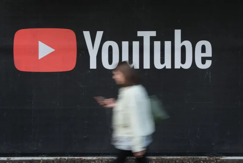 BERLIN, GERMANY - SEPTEMBER 27: A young woman with a smartphone walks past a billboard advertisement for YouTube on September 27, 2019 in Berlin, Germany. YouTube has evolved as the world's largest platform for sharing video clips. (Photo by Sean Gallup/Getty Images)