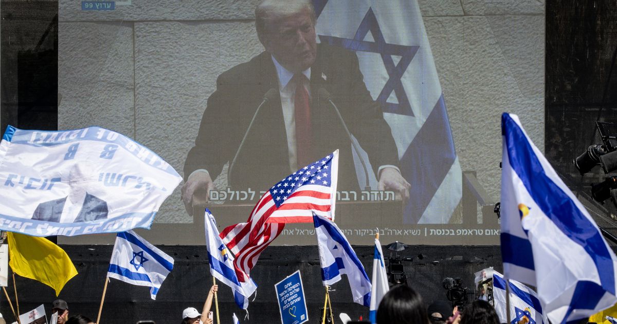 People watch President Donald Trump address the Knesset, Israel's parliament, on a giant screen in Hostages Square in Tel Aviv, Israel, on Monday.
