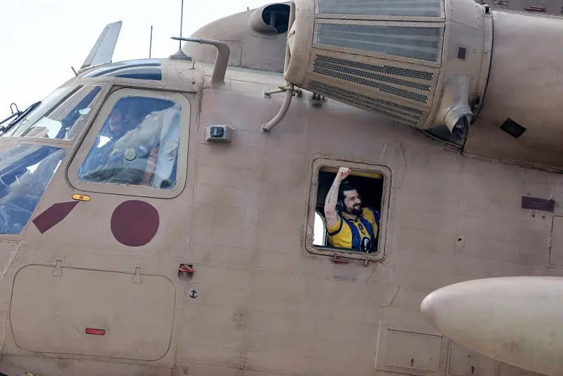 TOPSHOT - Ziv Berman, one of the released Israeli hostages formerly held captive in Gaza since the 2023 October 7 attacks by Palestinian militants, gestures from the window of an Israeli CH-53 Sea Stallion military helicopter at Sheba Tel-HaShomer Medical Centre in Ramat Gan on October 13, 2025. (Photo by Ahmad GHARABLI / AFP) (Photo by AHMAD GHARABLI/AFP via Getty Images)