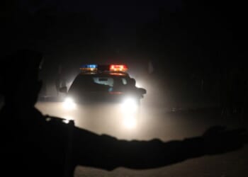 A police officer gestures as a police car runs on a street at night on November 28, 2017 in Ouagadougou. (Photo by LUDOVIC MARIN / AFP) (Photo by LUDOVIC MARIN/AFP via Getty Images)