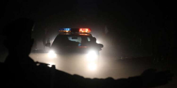 A police officer gestures as a police car runs on a street at night on November 28, 2017 in Ouagadougou. (Photo by LUDOVIC MARIN / AFP) (Photo by LUDOVIC MARIN/AFP via Getty Images)