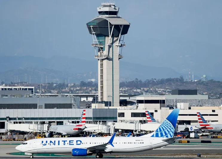LOS ANGELES, CALIFORNIA - OCTOBER 22: A United plane taxis in front of the air traffic control tower at Los Angeles International Airport on October 22, 2025 in Los Angeles, California. The Secretary of Transportation stated yesterday that air traffic controllers could stop receiving a paycheck next week while the federal government shutdown continues. (Photo by Mario Tama/Getty Images)