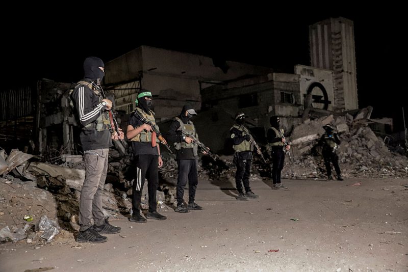 Hamas militants stand guard as vehicles of the International Committee of the Red Cross (not pictured) carry the bodies of hostages held in Gaza since the deadly October 7, 2023, attack, after their transfer by Hamas under a ceasefire and hostage-prisoner exchange agreement between Hamas and Israel, in Gaza City, Gaza Strip, on October 15, 2025. (Photo by Abood Abusalama / Middle East Images via AFP) (Photo by ABOOD ABUSALAMA/Middle East Images/AFP via Getty Images)