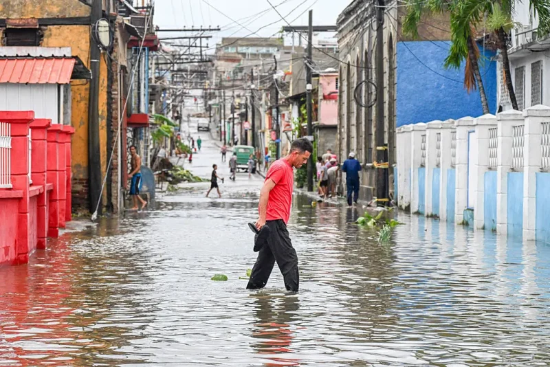 A man walks through a flooded street in a neighborhood affected by Hurricane Melissa in Santiago de Cuba on October 29, 2025. A powerful Hurricane Melissa made landfall in eastern Cuba on Wednesday, causing damage and flooding to homes and streets in Santiago de Cuba province, an AFP team on the ground reported. (Photo by YAMIL LAGE / AFP) (Photo by YAMIL LAGE/AFP via Getty Images)