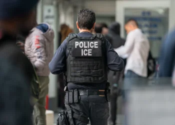 NEW YORK, NEW YORK - JUNE 6: An ICE agent monitors hundreds of asylum seekers being processed upon entering the Jacob K. Javits Federal Building on June 6, 2023 in New York City. New York City has provided sanctuary to over 46,000 asylum seekers since 2013, when the city passed a law prohibiting city agencies from cooperating with federal immigration enforcement agencies unless there is a warrant for the person