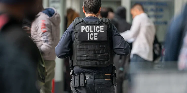 NEW YORK, NEW YORK - JUNE 6: An ICE agent monitors hundreds of asylum seekers being processed upon entering the Jacob K. Javits Federal Building on June 6, 2023 in New York City. New York City has provided sanctuary to over 46,000 asylum seekers since 2013, when the city passed a law prohibiting city agencies from cooperating with federal immigration enforcement agencies unless there is a warrant for the person