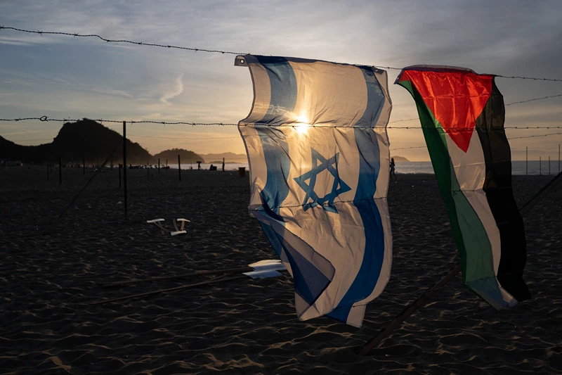 An Israeli and a Palestinian flag hang on an installation set up by members of the Brazilian NGO Rio de Paz at Copacabana beach in Rio de Janeiro, Brazil, on October 4, 2025, featuring photos of Israeli children killed in the bloody October 7, 2023, attack by Hamas on Israel, Palestinian children killed in Israeli bombardments of the Gaza Strip in retaliation, and Brazilian children killed by stray bullets during police operations. The demonstration, featuring 200 photos of Israeli, Palestinian and Brazilian children, denounced the violence that cuts lives short and steals childhoods. (Photo by Pablo PORCIUNCULA / AFP) (Photo by PABLO PORCIUNCULA/AFP via Getty Images)