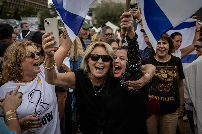 TEL AVIV, ISRAEL - OCTOBER 09: People gather and wave flags in what's known as Hostages Square as they react to the news of the Gaza peace deal on October 09, 2025 in Tel Aviv, Israel. Overnight, the US president announced that Israel and Hamas had agreed to the first phase of a ceasefire plan that would see the release of hostages - held in Gaza after their capture on Oct. 7, 2023 - in the coming days. Israel's government is meeting today to formally approve the deal. (Photo by Chris McGrath/Getty Images)