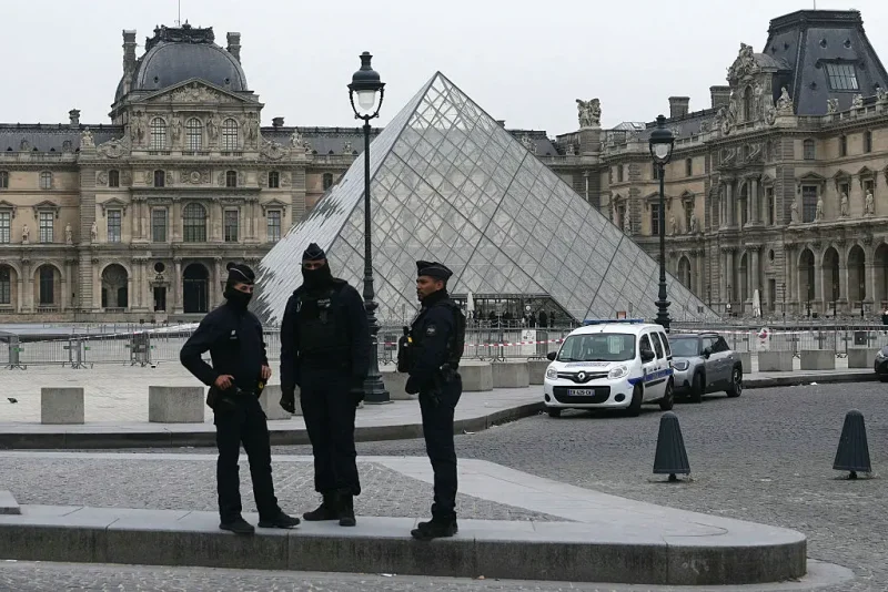 French police officers stand in front of the Louvre Museum after robbery, in Paris on October 19, 2025. Robbers broke in to the Louvre and fled with jewellery on October 19, 2025 morning, a source close to the case said, adding that its value was still being evaluated. A police source said an unknown number of thieves arrived on a scooter armed with small chainsaws and used a goods lift to reach the room they were targeting. (Photo by Dimitar DILKOFF / AFP) / -- IMAGE RESTRICTED TO EDITORIAL USE - STRICTLY NO COMMERCIAL USE -- (Photo by DIMITAR DILKOFF/AFP via Getty Images)
