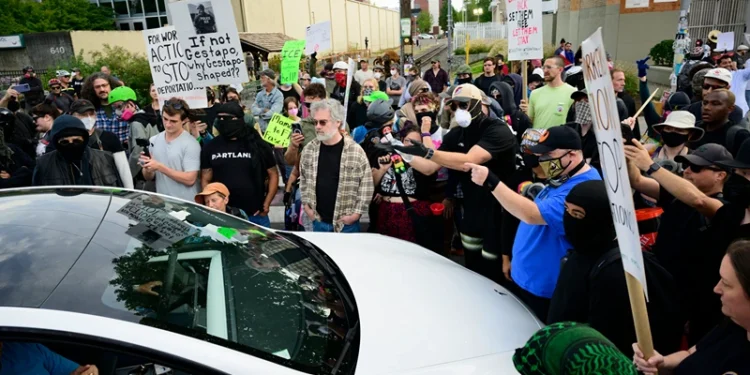 PORTLAND, OREGON - SEPTEMBER 28: Protesters engage a vehicle that drove into the crowd outside of the U.S. Immigration and Customs Enforcement building on September 28, 2025 in Portland, Oregon. In a Truth Social post on September 27th, President Trump authorized the deployment of military troops to "protect War ravaged Portland, and any of our ICE Facilities under siege from attack by Antifa, and other domestic terrorists." (Photo by Mathieu Lewis-Rolland/Getty Images)