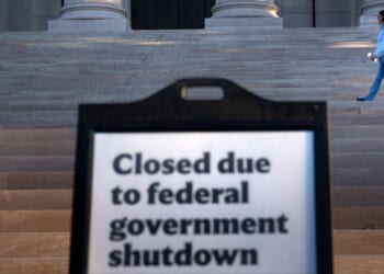 A woman walks past a sign indicating the National Gallery of Art in Washington, D.C., is closed Oct. 6 as the U.S. government continues its shutdown.
