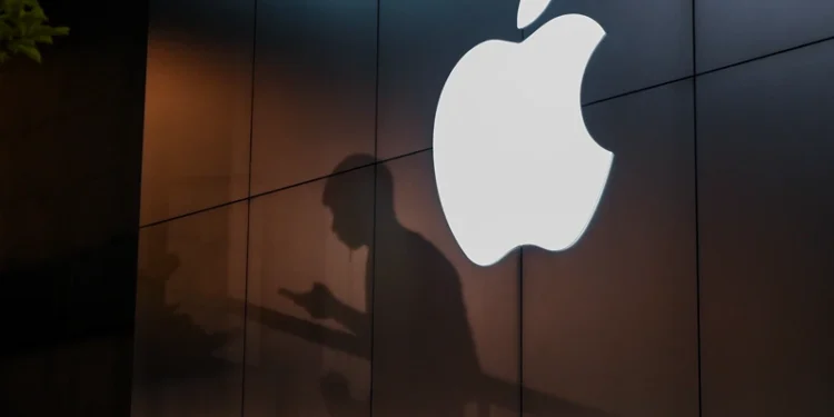 The shadow of a man is cast on the wall of an Apple store as he uses his mobile phone in Beijing on August 26, 2019. There were signs of a thaw in frosty trade-war tensions between China and the US on August 26 as President Donald Trump said delegations would "very shortly" resume talks and Beijing