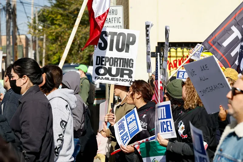 Protesters hold signs against Immigration and Customs Enforcement during the "ICE and DHS Out of Little Village" demonstration at the predominantly Mexican-American neighborhood of Little Village, also known as "La Villita", in Chicago, Illinois on October 25, 2025. US President Donald Trump's administration has asked the Supreme Court to lift lower court rulings blocking his deployment of the National Guard in Chicago. Trump has ordered hundreds of National Guard troops to Chicago, claiming they are needed to combat crime and to protect immigration agents and facilities in America's third-largest city. (Photo by KAMIL KRZACZYNSKI / AFP) (Photo by KAMIL KRZACZYNSKI/AFP via Getty Images)