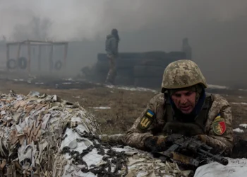 A Ukrainian serviceman of the 24th Mechanized Brigade takes position by sandbags covered with camouflage netting as smoke billows nearby, during training drill at an undisclosed location in the eastern region of Ukraine on March 4, 2025, amid the Russian invasion of Ukraine. (Photo by Tetiana DZHAFAROVA / AFP) (Photo by TETIANA DZHAFAROVA/AFP via Getty Images)