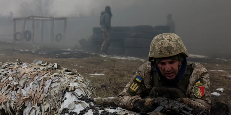 A Ukrainian serviceman of the 24th Mechanized Brigade takes position by sandbags covered with camouflage netting as smoke billows nearby, during training drill at an undisclosed location in the eastern region of Ukraine on March 4, 2025, amid the Russian invasion of Ukraine. (Photo by Tetiana DZHAFAROVA / AFP) (Photo by TETIANA DZHAFAROVA/AFP via Getty Images)