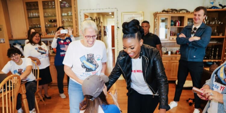 Stephanie Miller greets Texas Democratic Rep. Jasmine Crockett’s feet at an event.