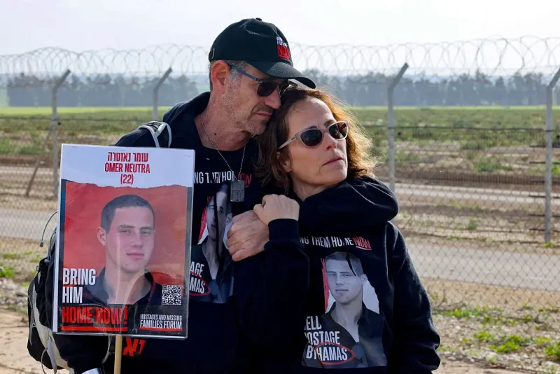 Relatives of Israeli hostages held by the Palestinian Hamas movement carry a picture of Omer Neutra, 22, in Kibbutz Nirim along the fence on the Gaza border, equipped with powerful loudspeakers hanging from cranes, in an effort to get messages of hope across to them as their time in captivity nears to 100 days, on January 11, 2024. The conflict triggered by Hamas's deadly October 7 attack on Israel has caused massive destruction in the Gaza Strip, killing tens of thousands and leaving residents on the brink of famine. Much of the territory has become unrecognisable, as entire neighbourhoods which were once bustling with people, cars and donkey-drawn carts have been reduced to rubble. (Photo by JACK GUEZ / AFP) (Photo by JACK GUEZ/AFP via Getty Images)