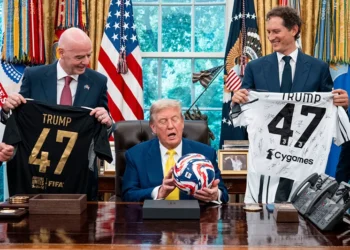 US President Donald Trump (C), flanked by Chairperson of Ferrari John Elkann (R) and FIFA President Gianni Infantino, holds a ball as he makes remarks in the Oval Office of the White House during a visit by members of Italian soccer club Juventus in Washington, DC, on June 18, 2025. Juventus will play Emirati club Al-Ain in the 2025 FIFA Club World Cup at Washington