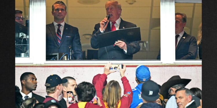 President Donald Trump, center, alongside Secretary of Defense Pete Hegseth, left, and Washington Commanders owner Josh Harris, right, reads the oath for people re-enlisting to the U.S. Army Sunday as he attends the NFL game between the Washington Commanders and the Detroit Lions in Landover, Maryland.
