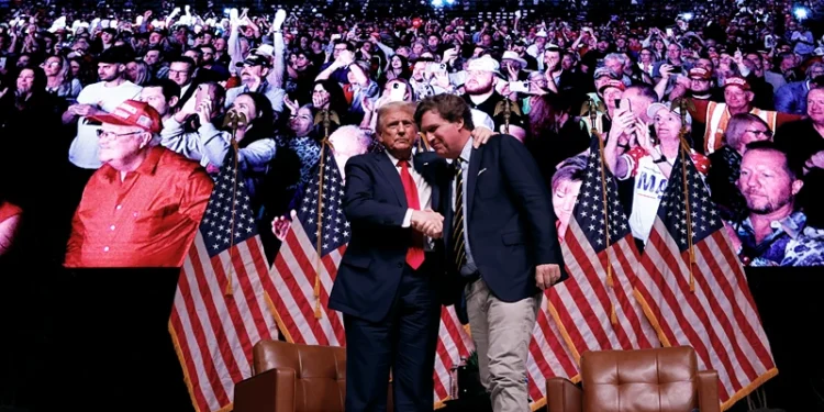 PHOENIX, ARIZONA - OCTOBER 31: Republican presidential nominee, former President Donald Trump shakes hands with Tucker Carlson at the conclusion of a conversation during Carlson