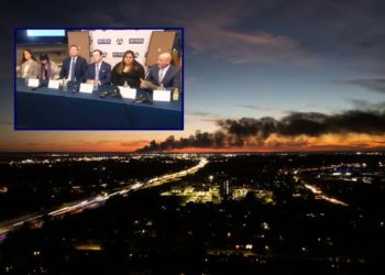 (Background) Smoke rises from the site of a UPS cargo plane crash near the UPS Worldport at Louisville Muhammad Ali International Airport in Louisville, Kentucky, on November 4, 2025. The death toll from a UPS cargo plane crashing in Louisville has risen to nine with more fatalities feared, Kentucky