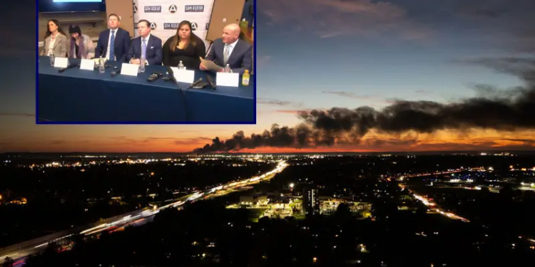 (Background) Smoke rises from the site of a UPS cargo plane crash near the UPS Worldport at Louisville Muhammad Ali International Airport in Louisville, Kentucky, on November 4, 2025. The death toll from a UPS cargo plane crashing in Louisville has risen to nine with more fatalities feared, Kentucky