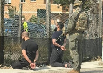 In a photograph shared on X, two men are seen detained with zipties as Armed Australian SWAT members loom behind them. (Photo: NDTV WORLD Via X)
