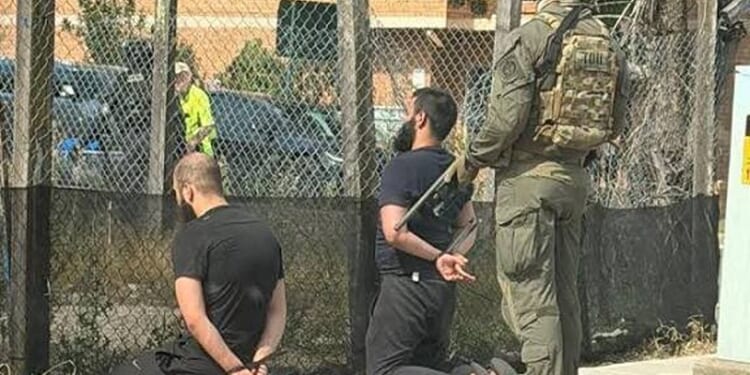 In a photograph shared on X, two men are seen detained with zipties as Armed Australian SWAT members loom behind them. (Photo: NDTV WORLD Via X)
