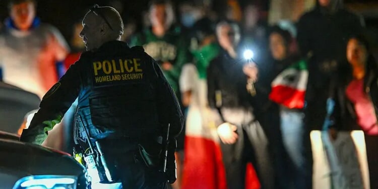 A Department of Homeland Security agent stands guard as protesters demonstrate against recent raids conducted by the US Immigration and Customs Enforcement (ICE) outside the DHS office in Charlotte, North Carolina, on November 16, 2025. Federal immigration officers began immigration enforcement operations in Charlotte on November 15, they confirmed in a statement. "We are surging DHS law enforcement to Charlotte to ensure Americans are safe and public safety threats are removed," Assistant Homeland Security Secretary Tricia McLaughlin said. US President Donald Trump has made deporting undocumented immigrants a key priority for his second term, after successfully campaigning against an alleged "invasion" by criminals. (Photo by Peter Zay / AFP) (Photo by PETER ZAY/AFP via Getty Images)