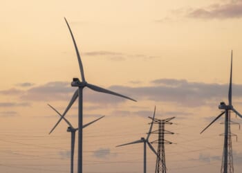 A wind farm with electricity pylons against the backdrop of an orange sky at the end of the day in Beauvilliers, France, on Nov. 25, 2025.