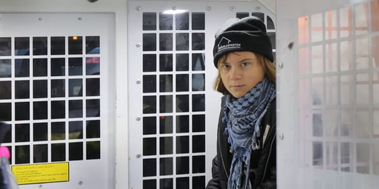 Greta Thunberg is arrested and sits in the back of a police van outside the offices of Aspen Insurance on Dec. 23, 2025, in London, England.