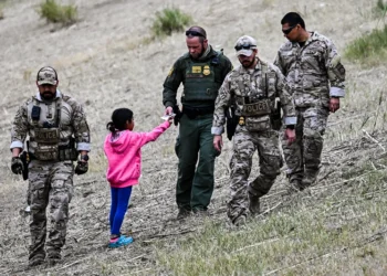 TOPSHOT - A US Customs and Border Protection officer gives food to an immigrant child waiting to be processed at a US Border Patrol transit center after crossing the border from Mexico at Eagle Pass, Texas on December 22, 2023. Texas Republican Governor Greg Abbott signed a bill on December 18, 2023 that would allow state police to arrest and deport migrants who cross illegally into the US from Mexico. (Photo by CHANDAN KHANNA / AFP) (Photo by CHANDAN KHANNA/AFP via Getty Images)