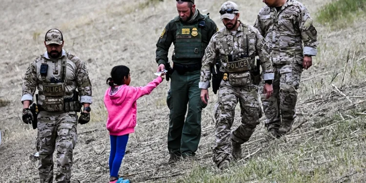 TOPSHOT - A US Customs and Border Protection officer gives food to an immigrant child waiting to be processed at a US Border Patrol transit center after crossing the border from Mexico at Eagle Pass, Texas on December 22, 2023. Texas Republican Governor Greg Abbott signed a bill on December 18, 2023 that would allow state police to arrest and deport migrants who cross illegally into the US from Mexico. (Photo by CHANDAN KHANNA / AFP) (Photo by CHANDAN KHANNA/AFP via Getty Images)