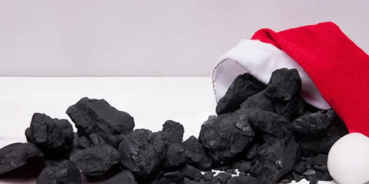 A pile of coal emerges from a Santa Claus hat.