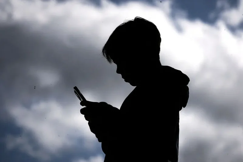 A 14-year-old boy posing at his home near Gosford as he looks at social media on his mobile phone. Tech giants Meta and TikTok said they will obey Australia's under-16 social media ban but warned the landmark laws could prove difficult to enforce. Australia will from December 10 force social media platforms such as Facebook, Instagram and TikTok to remove users under the age of 16. (Photo by David GRAY / AFP) (Photo by DAVID GRAY/AFP via Getty Images)