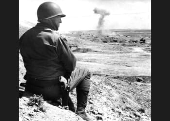 American military commander Lieutenant General George S. Patton (1885 - 1945) sits on the sand and watches a tank battle in Tunisia, 1943.
