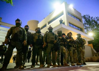 Federal agents, including members of the Department of Homeland Security, Border Patrol, and others, stand guard outside an Immigration and Customs Enforcement (ICE) facility in downtown Portland, Oregon, on October 6, 2025. President Donald Trump threatened on October 6, 2025, to use emergency powers against rebellion to deploy more troops into Democratic-led US cities, intensifying his rhetoric as his attempts to mobilize the military face legal challenges. Trump openly mulled use of the Insurrection Act after a federal judge in Oregon temporarily halted a National Guard deployment in Portland, while another judge in Illinois allowed a similar move to proceed for now in Chicago. (Photo by Mathieu Lewis-Rolland / AFP) (Photo by MATHIEU LEWIS-ROLLAND/AFP via Getty Images)