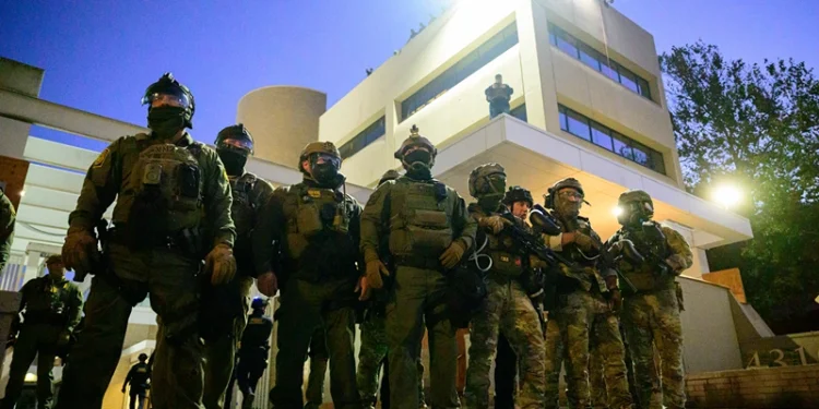 Federal agents, including members of the Department of Homeland Security, Border Patrol, and others, stand guard outside an Immigration and Customs Enforcement (ICE) facility in downtown Portland, Oregon, on October 6, 2025. President Donald Trump threatened on October 6, 2025, to use emergency powers against rebellion to deploy more troops into Democratic-led US cities, intensifying his rhetoric as his attempts to mobilize the military face legal challenges. Trump openly mulled use of the Insurrection Act after a federal judge in Oregon temporarily halted a National Guard deployment in Portland, while another judge in Illinois allowed a similar move to proceed for now in Chicago. (Photo by Mathieu Lewis-Rolland / AFP) (Photo by MATHIEU LEWIS-ROLLAND/AFP via Getty Images)
