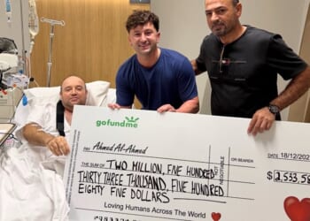 A picture shared to X shows Zachery Dereniowski (M) handing Ahmed al Ahmed (R) a check of $2,544,585 AUS, about $1.6 million USD, while he recovers in a hospital bed. (Photo: 6ixbuzztv via X)