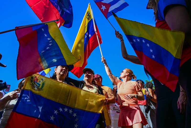 TOPSHOT - People react to the news of the capture of Venezuelan President Nicolas Maduro, after US military actions in Venezuela this morning, in Doral, Florida, near Miami on January 3, 2026. President Trump said Saturday that US forces had captured Venezuelan leader Nicolas Maduro after launching a "large scale strike" on the South American country. (Photo by GIORGIO VIERA / AFP via Getty Images)