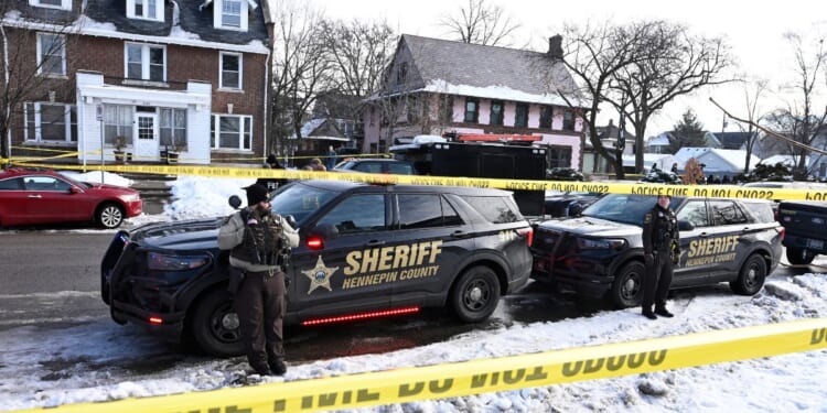 Members of the Hennepin County Sheriff's Office look on as people gather near the scene of a shooting Wednesday by an ICE agent during federal law enforcement operations in Minneapolis, Minnesota.