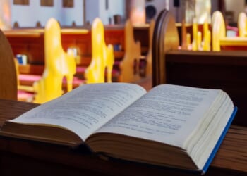 Open Bible is seen in a stock photo on a church pew.