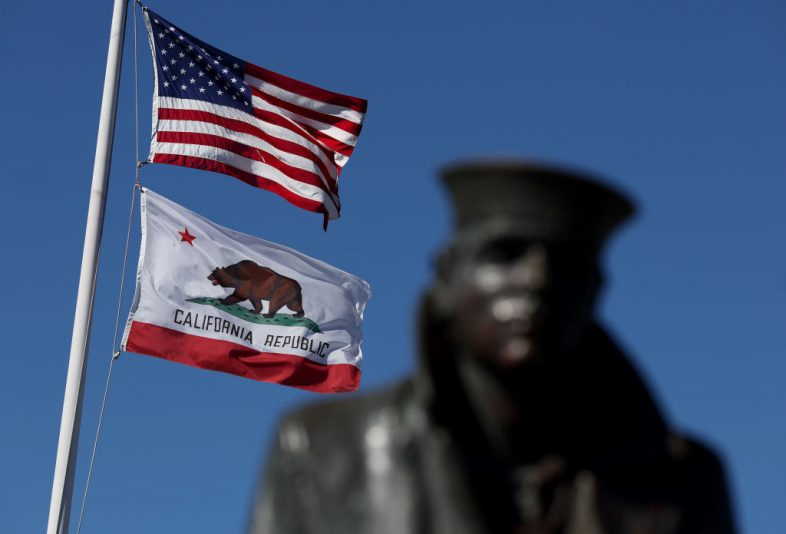 SAUSALITO, CALIFORNIA - OCTOBER 24: An American flag flies with the California State flag next to the Lone Sailor statue on October 24, 2022 in Sausalito, California. The State of California, currently the fifth largest economy in the world, is likely to overtake Germany as the fourth largest economy in the near future as the state's gross domestic product is continuing to rise with steady growth. (Photo by Justin Sullivan/Getty Images)