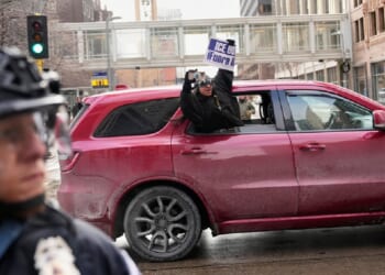 A protester holds a sign reading, "ICE Out," out of a car in Minneapolis on Saturday.